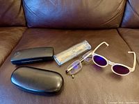 Full lot view: Goodr sunglasses, reading glasses, two black hard cases, clear case