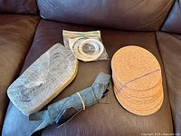 All items displayed on sofa: cork pads stack, adhesive rings bag, wrapped block, rolled suede strip