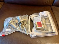 Facto packaged lever lockset and open bag of assorted door hardware parts displayed on brown surface