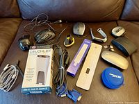 Entire lot spread on brown sofa showing mice, cables, Couchlet box and other items