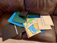 All binders, folders, sleeves and pads spread on brown sofa
