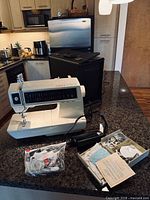 Singer sewing machine on countertop with accessories and case visible