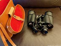 binoculars next to open leather case with red lining