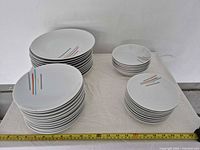 Stacks of dinner, luncheon and side plates with cereal bowls displaying Airport stripe pattern