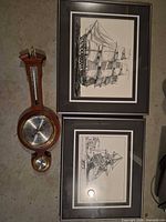 Group shot of two framed prints and wooden barometer