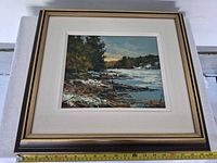 Front view of framed oil painting with measuring tape showing width