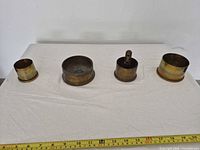 Four brass shell ashtrays lined on table with ruler