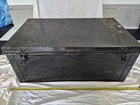 Front view of black metal trunk with measuring tape