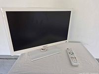 Front view of Samsung white TV with remote on stand