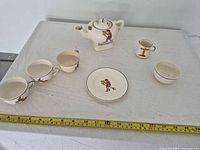 Full view of seven-piece tea set on table with measuring tape for scale