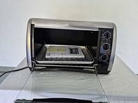 Toaster oven open showing interior tray and paperwork