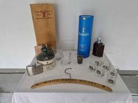 All items arranged on table including box, bottle, glasses, flasks, hanger and case