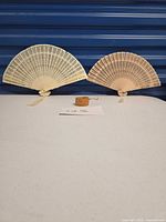 Full lot showing two opened carved wood fans and carved wooden bangle