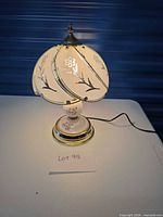 Lamp illuminated showing glass shade, porcelain base and brass accents