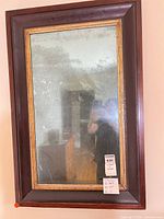 Front view of antique wall mirror with dark wood frame and gold inner trim