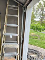 Tall aluminum ladder and small step stool inside garage