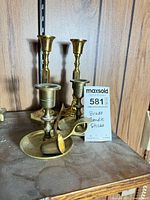 Group shot showing all brass candlesticks and snuffer