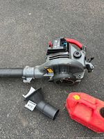 Craftsman handheld blower with attached tube, spare nozzle and red fuel can