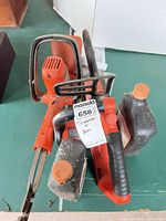 Top view of chainsaw, bar cover, two oil bottles
