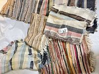 Group of assorted small handwoven cotton rag rugs showing stripe patterns and fringed edges