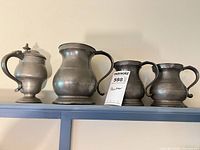 Four pewter vessels on shelf