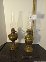 Pair of brass hurricane lamps with glass chimneys, ruler for scale