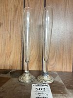 Front view of both etched glass bud vases on sterling bases