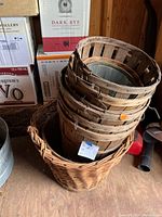 Stack of five wooden bushel baskets inside one large wicker basket