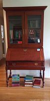 Front view of closed secretary desk showing glass-door hutch and closed drop-front, overall form and finish