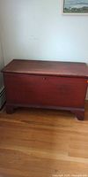 Closed view of red/mahogany hope chest on wood floor