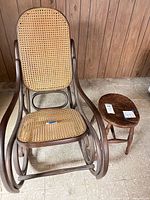 Front view of bentwood rocking chair showing cane seat/back and stool beside