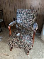 Front view of floral tapestry armchair showing upholstery pattern and wood arms