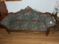 Front view of carved wood frame settee with floral upholstery