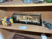 Shelf view showing diorama, tea tins, small figurine