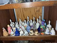 Full shelf view of roughly thirty assorted porcelain and one glass bell