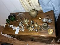 Overall lot view showing multiple metal bells and glass bottles on dresser