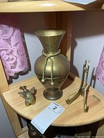 Brass vase, cherub figurine and plate stand grouped on shelf