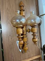 Full view of wooden wall double candle holder with both glass shades attached