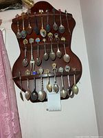 Full view of rack showing multiple souvenir spoons on three shelves