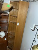 Full view of tall oak veneer corner cabinet showing height and shelves