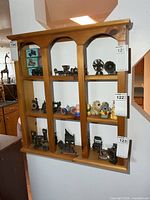 Front view of solid wood display shelf mounted on wall showing four tiers and arched top