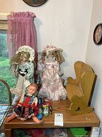 Group shot showing two porcelain dolls, plastic doll, and wooden rocker bench on shelf