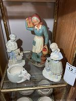 Group shot of three figurines and rabbit-handle planter on shelf