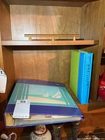 Shelf showing both binders: blue sailboat binder and green/blue 1st Day Issue binder