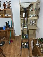 Full view of black metal floor lamp with frosted glass bowl shade and three square shelves