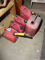 Group of five red plastic fuel cans on floor