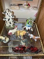 Group view showing all figurines on glass shelf, includes cow tower, horses, snow globe