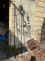 Both twisted metal stakes leaning against shed with sign attached