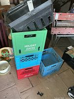 Stack showing green, blue and red branded milk crates with black shopping basket on top