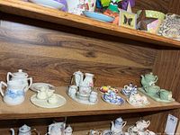 Multiple miniature tea sets arranged on shelf
